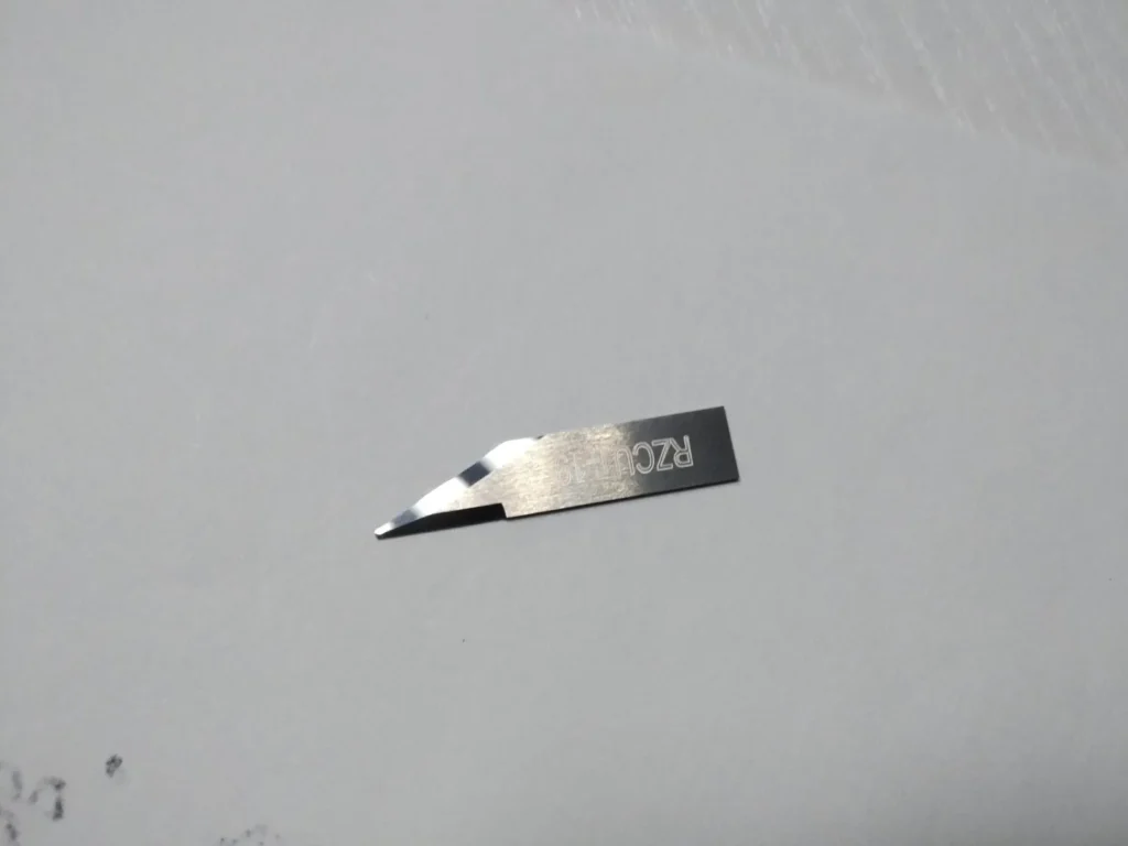 Reverse angle view of ZINGCUT-19 tungsten steel blade, showing polished edge and engraved text detail