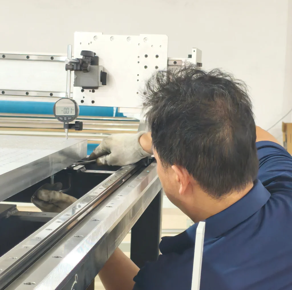 Factory worker uses dial indicator to precisely calibrate linear guide rail during ZINGCUT CNC cutting machine assembly