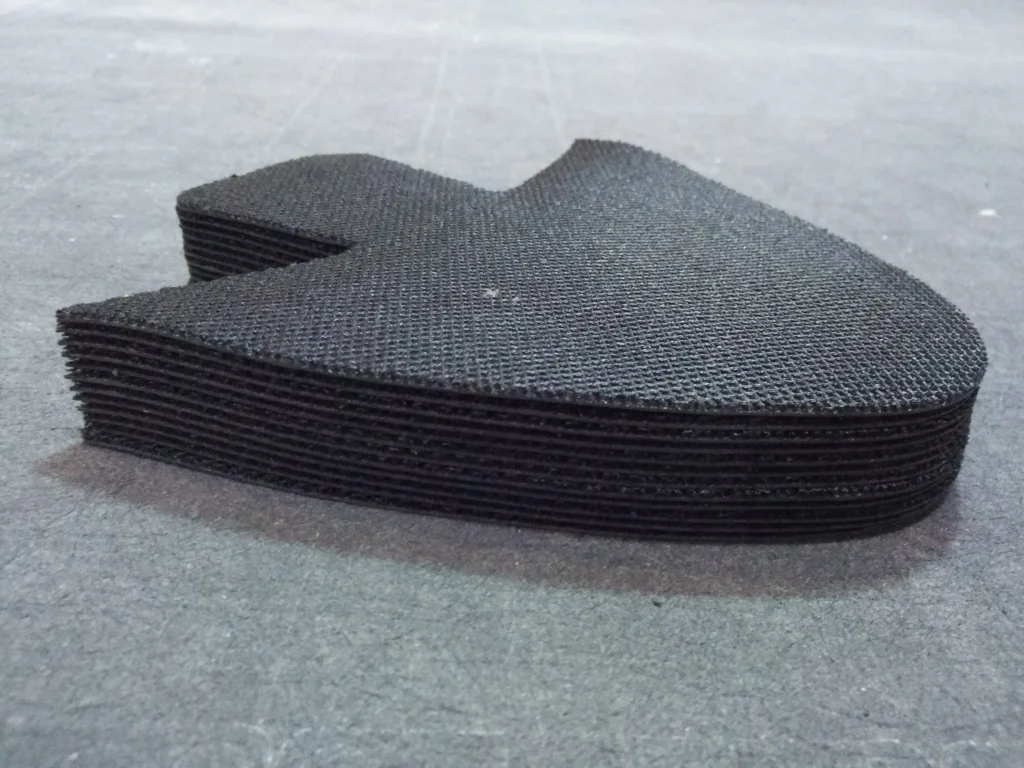 Stacked black knitted shoe upper cut pieces, multi-layer cutting sample processed by ZINGCUT digital cutter with tidy edges